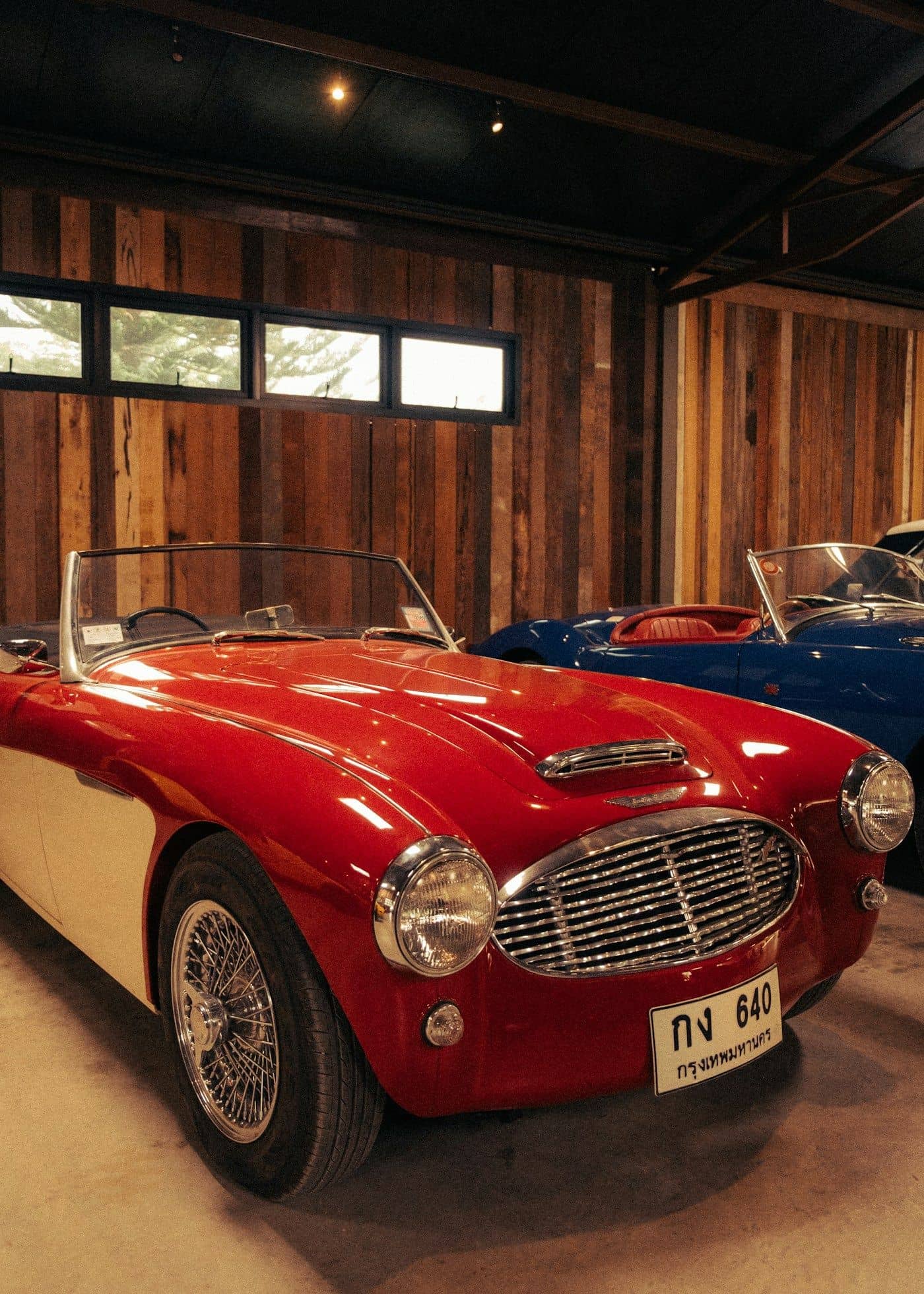 A red-and-white classic roadster beside a blue convertible